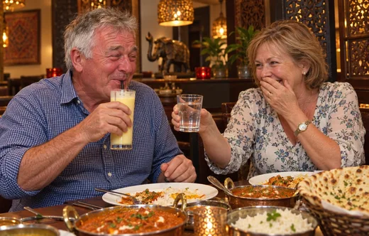 Couple over 60 laughing on a first date at an Indian restaurant